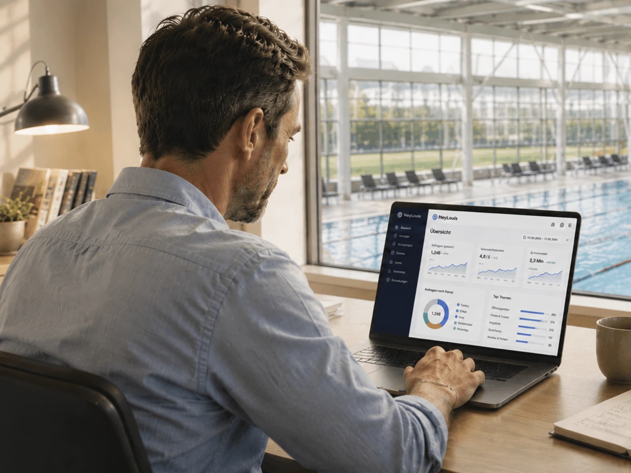 Ein Thermenmanager betrachtet am Laptop ein HeyLouis Dashboard mit Kennzahlen, während im Hintergrund eine helle Poolhalle zu sehen ist.